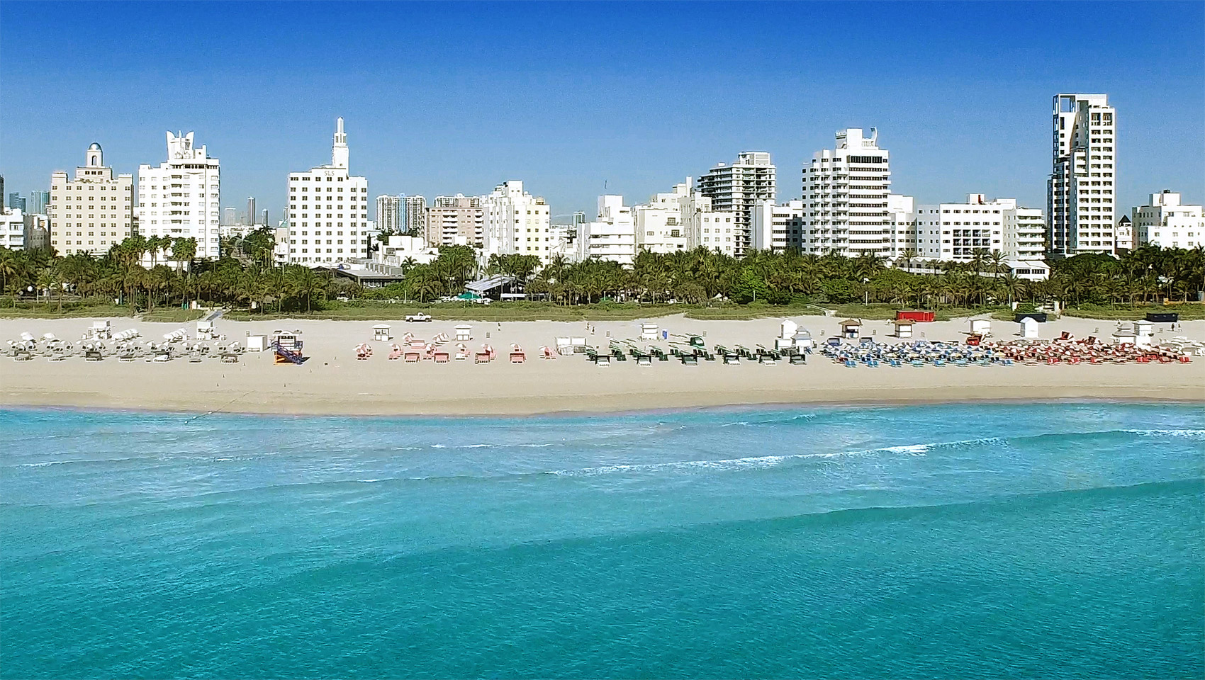 lounge chairs on a beach with hotels in the background