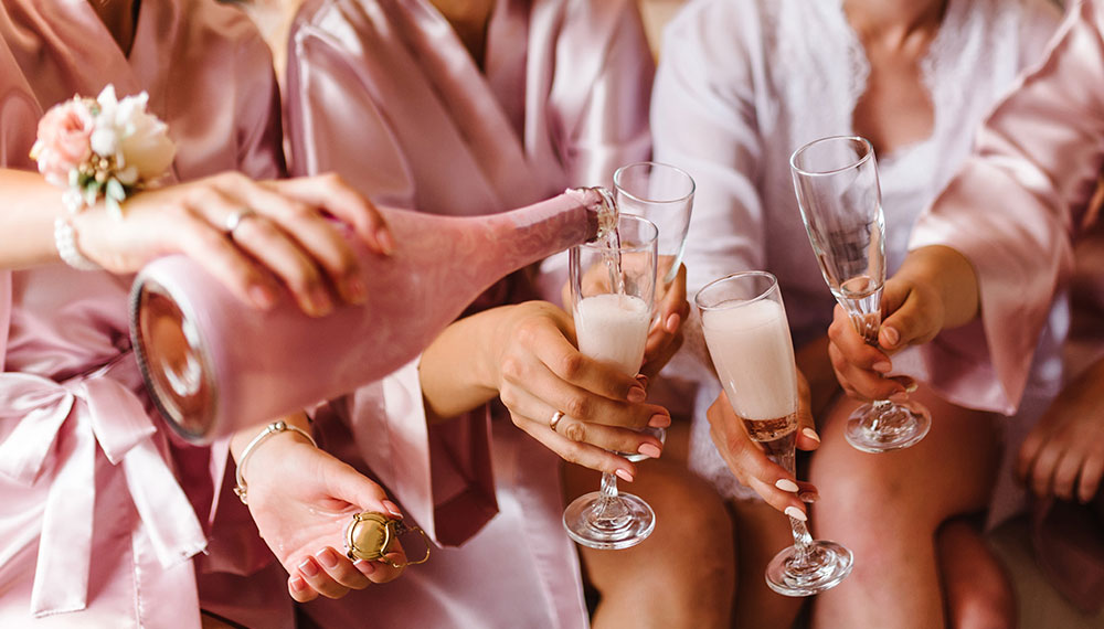 bride and bridesmaids in robes with champagne