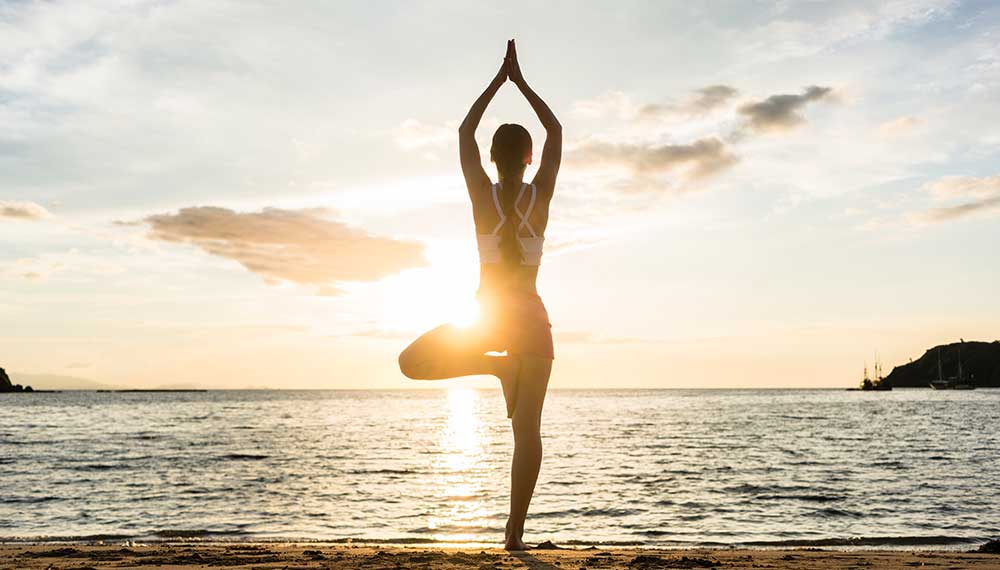 image of woman in yoga pose on beach