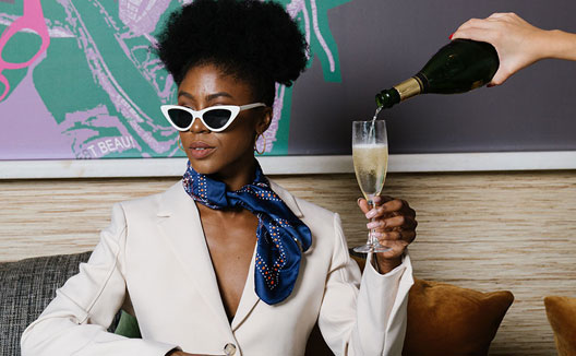 Woman in sunglasses being served Champagne